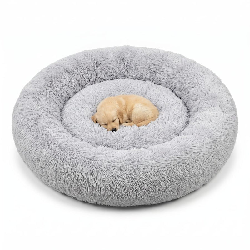 Golden retriever-valp som sover hopkurad mitt i en stor, ljusgrå CalmBed